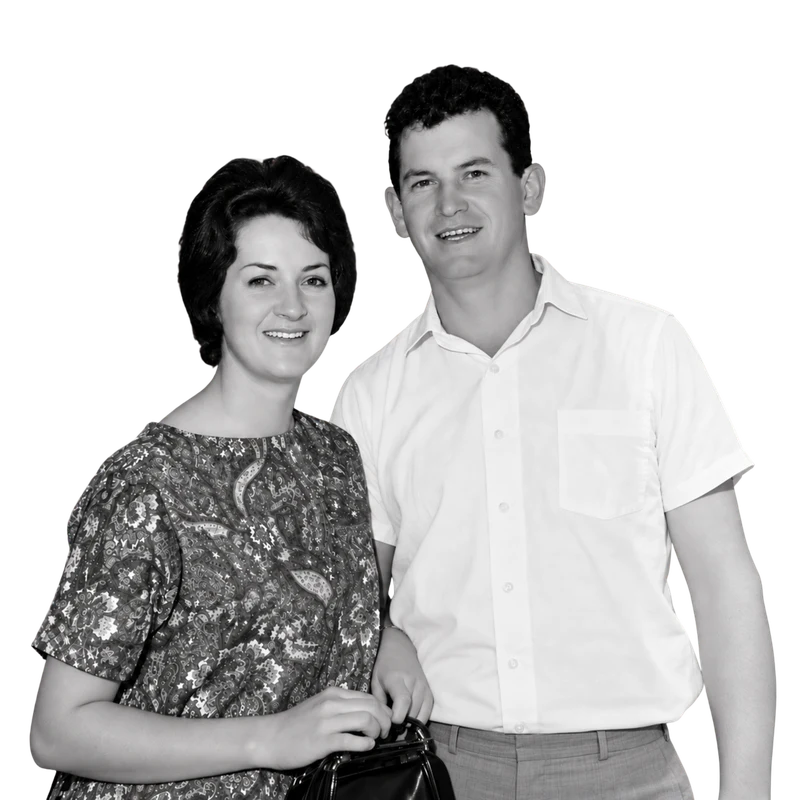 A young couple in the early 1960s, she in a patterned blouse holding a handbag, he in a white short-sleeved shirt.